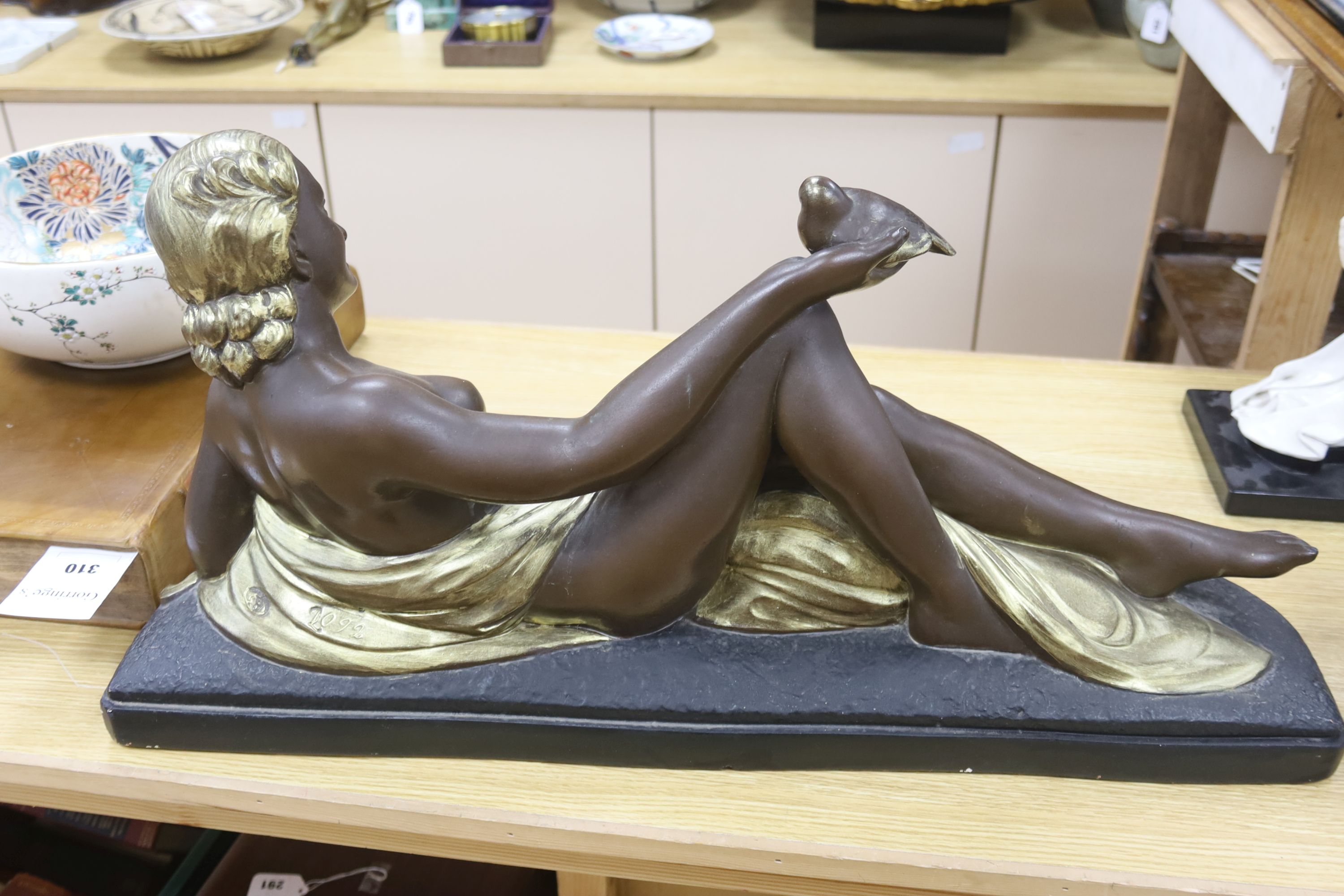 An Art Deco style painted plaster reclining nude holding a dove, length 75cm